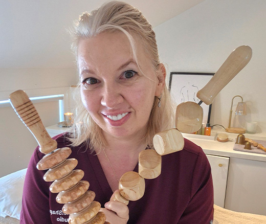 Erika holding wooden tools used for Colombian wood therapy and body sculpting.
